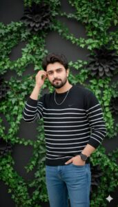 Young man wearing a black striped sweater and jeans standing casually in front of a decorative wall with green vines and black flower designs.